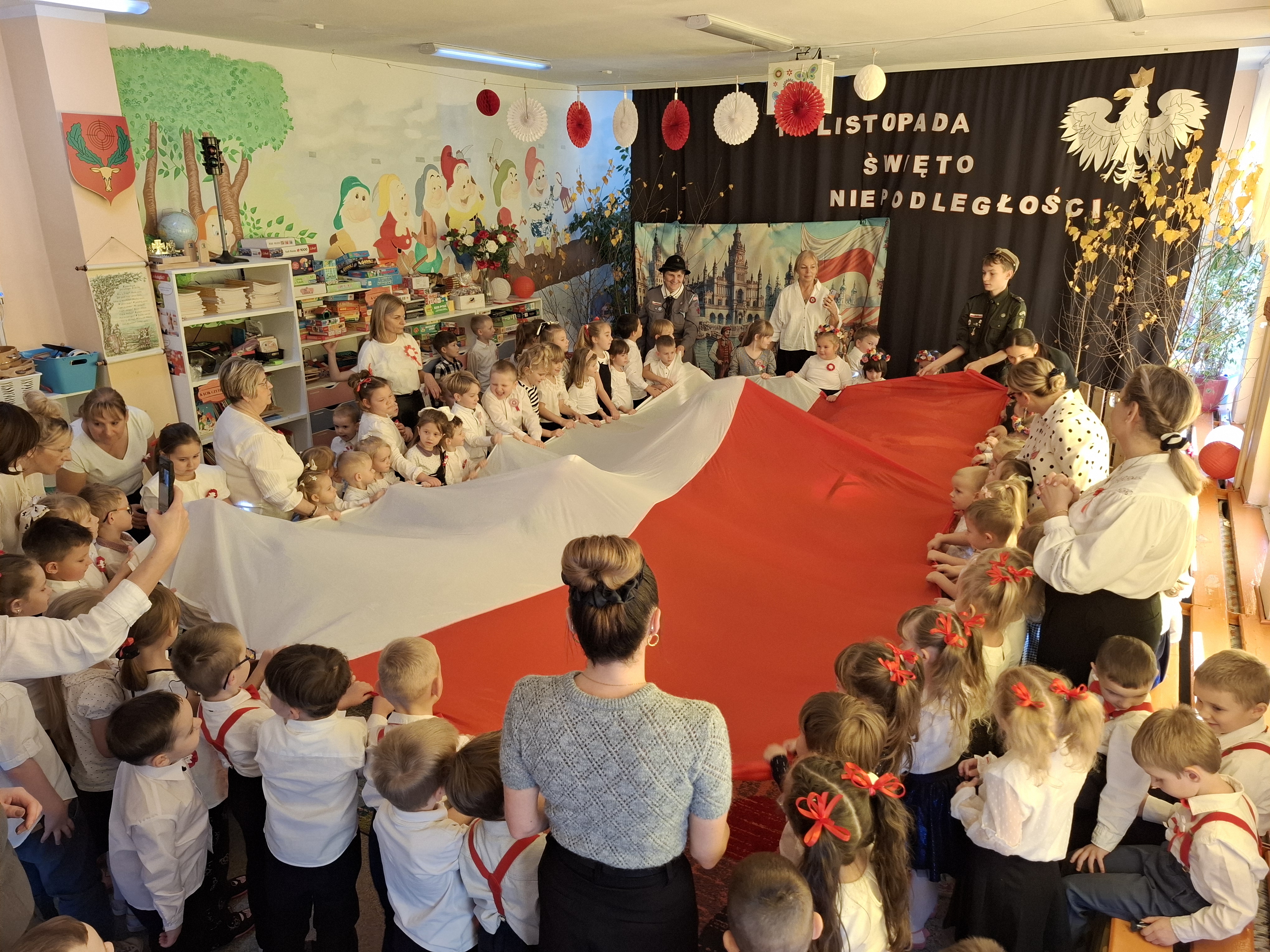 Dzieci wraz z kadra trzymają ogromną flagę