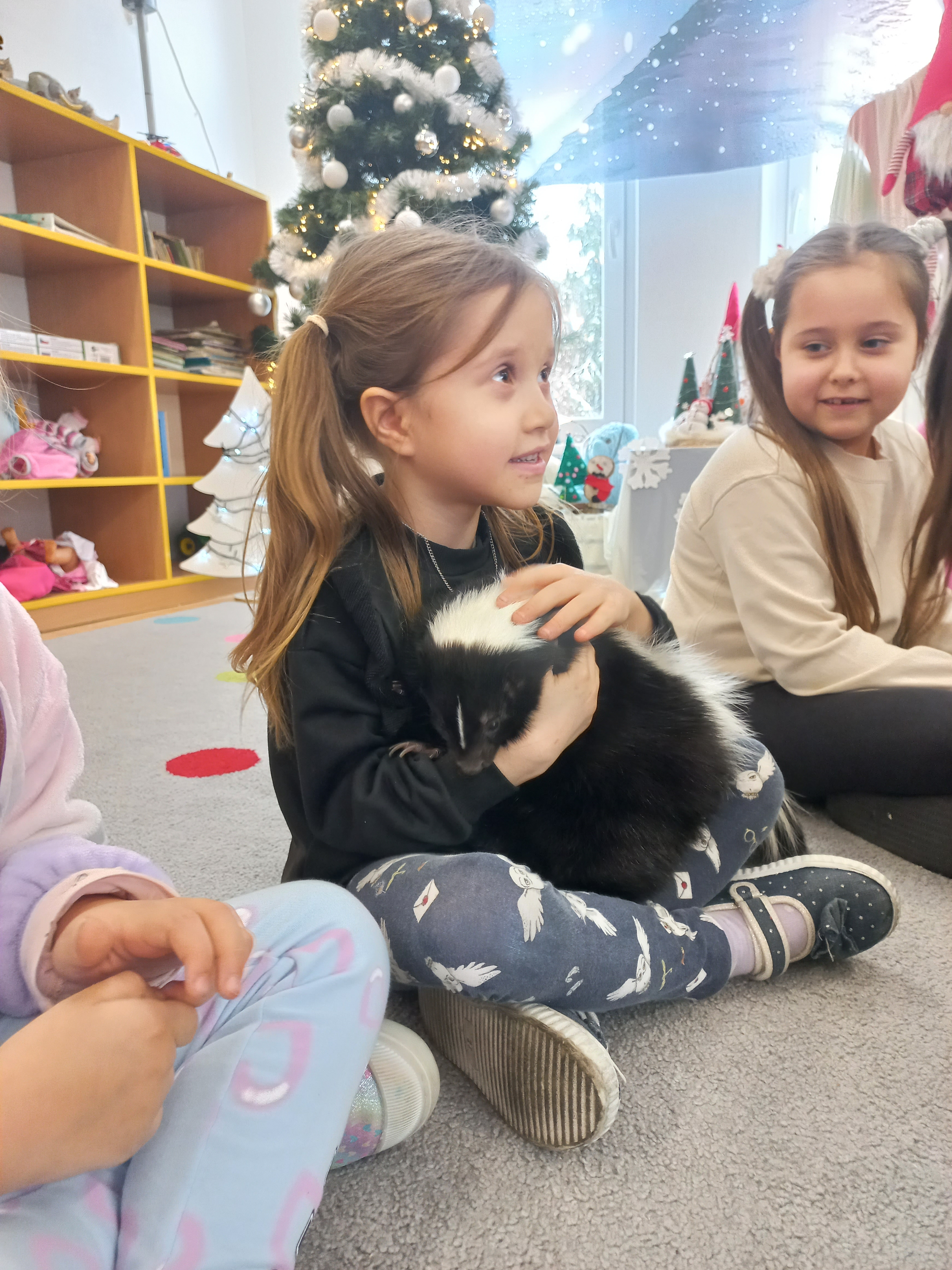 Dziewczynka trzyma na rękach skunksa