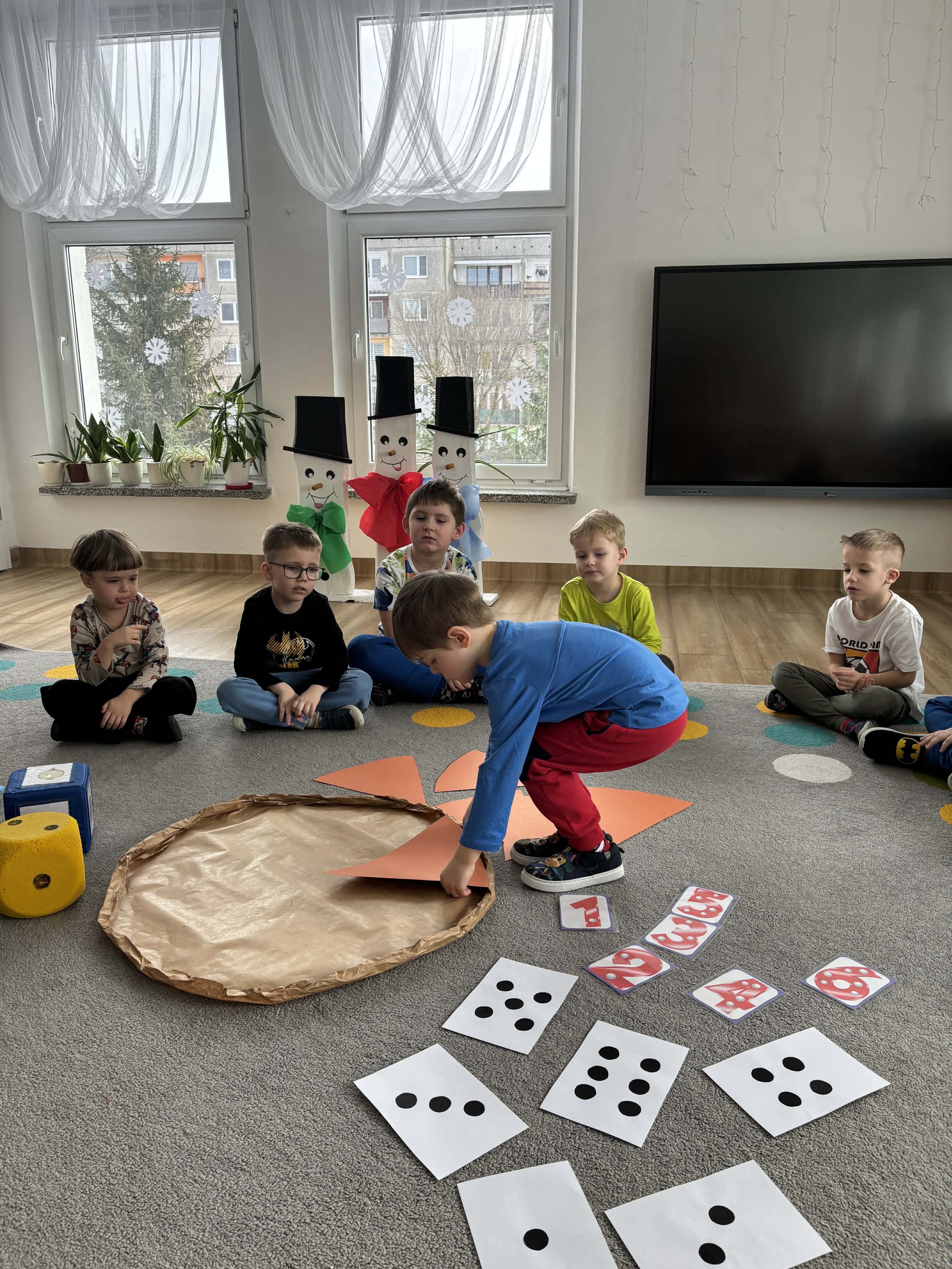 Chłopiec ładzie elementy na papierowej pizzy